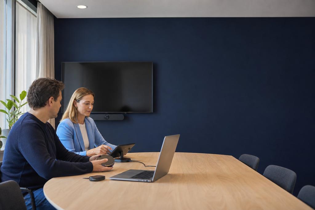 Illustratieve ICT-supportspecialist en medewerker die camera, microfoon, roomcontroller en schermdeling van een hybride vergaderruimte testen
